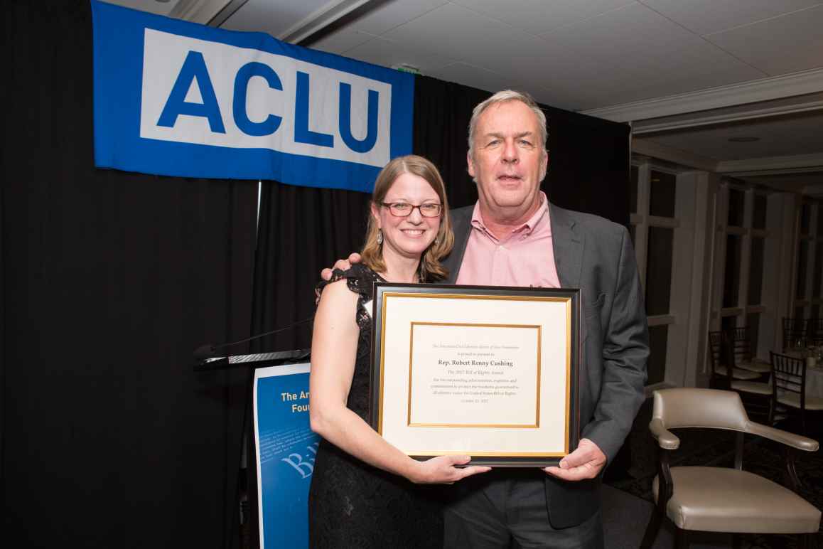 Devon Chaffee and Renny Cushing hold an award certificate with an ACLU banner in the background