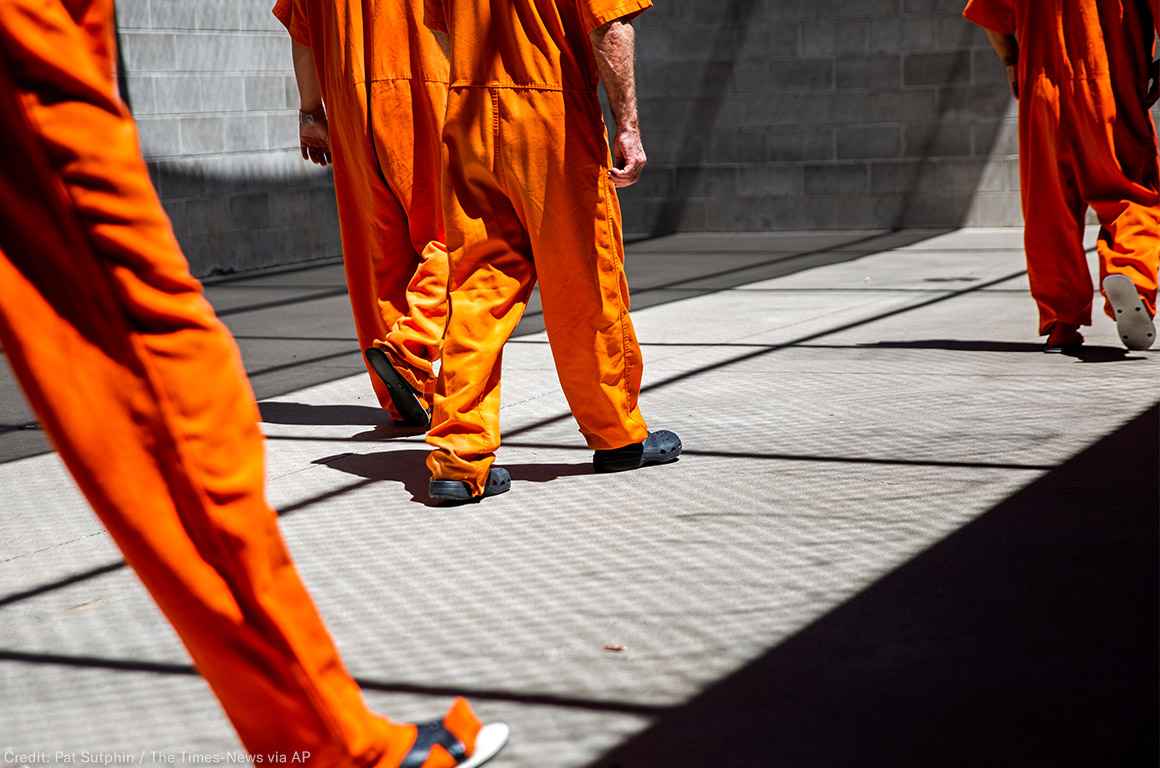 A group of incarcerated people walking a concrete yard